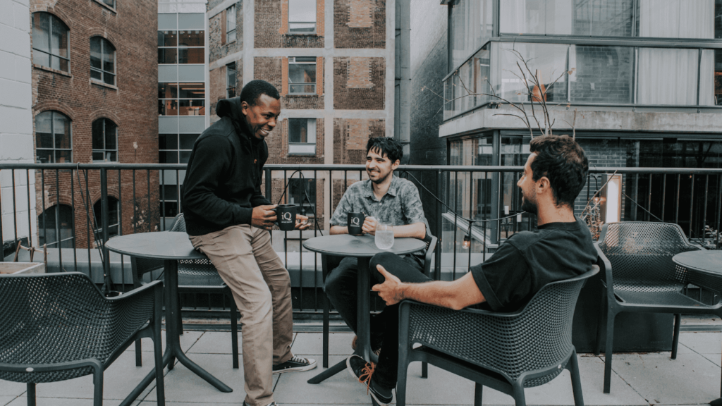 Men enjoying coffee and chatting in outdoor patio in coworking space